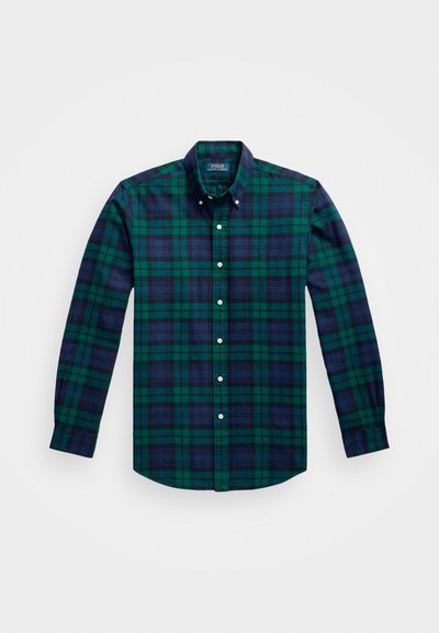 Camisa xadrez verde e azul-marinho com mangas longas, colarinho abotoado e botões brancos. Tecido suave com um padrão de textura. Pequeno logotipo no peito.