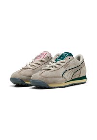 Sneakers in suede beige con accenti verdi e rosa, dotati di lacci bianchi, suola in gomma e un design vintage con strisce laterali.