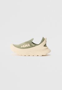 Hoka slip-on sneaker in olive green with a textured upper, cream-colored sole, and distinctive ridged design for enhanced support.