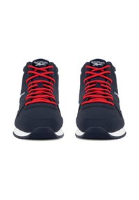 Pár tmavě modrých tenisek Reebok s jasně červenými šňůrkami, bílými mezipodešvami a černými texturovanými podrážkami směřujícími dopředu na bílém pozadí.