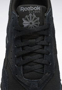 Baskets noires Reebok Classic en suède et mesh, avec lacets noirs et logo Reebok sur la languette et le côté.