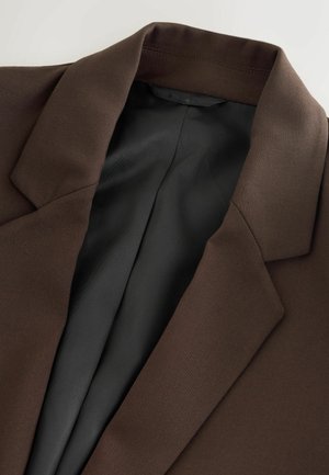 Pruun bleiser, millel on lõhikuga krae ja pehme tekstuur; siseruum on must ja ühtlase pinnaga, millel on puhas ja hästi istuv disain.