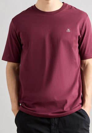 T-shirt color mogano realizzato in tessuto morbido, con collo rotondo e maniche corte. Piccolo logo ricamato sul petto, design minimalista.