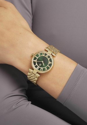 Orologio da polso in tonalità oro con un quadrante verde rotondo che presenta grandi lettere bianche. Il cinturino è in metallo intrecciato, caratterizzato da una finitura testurizzata.