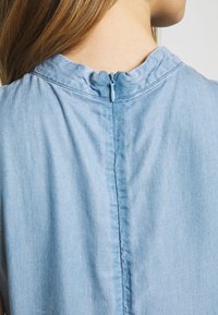 Lichtblauw chambray shirt met een geraffineerde kraag, voorzien van een rits aan de achterkant en een gladde textuur.