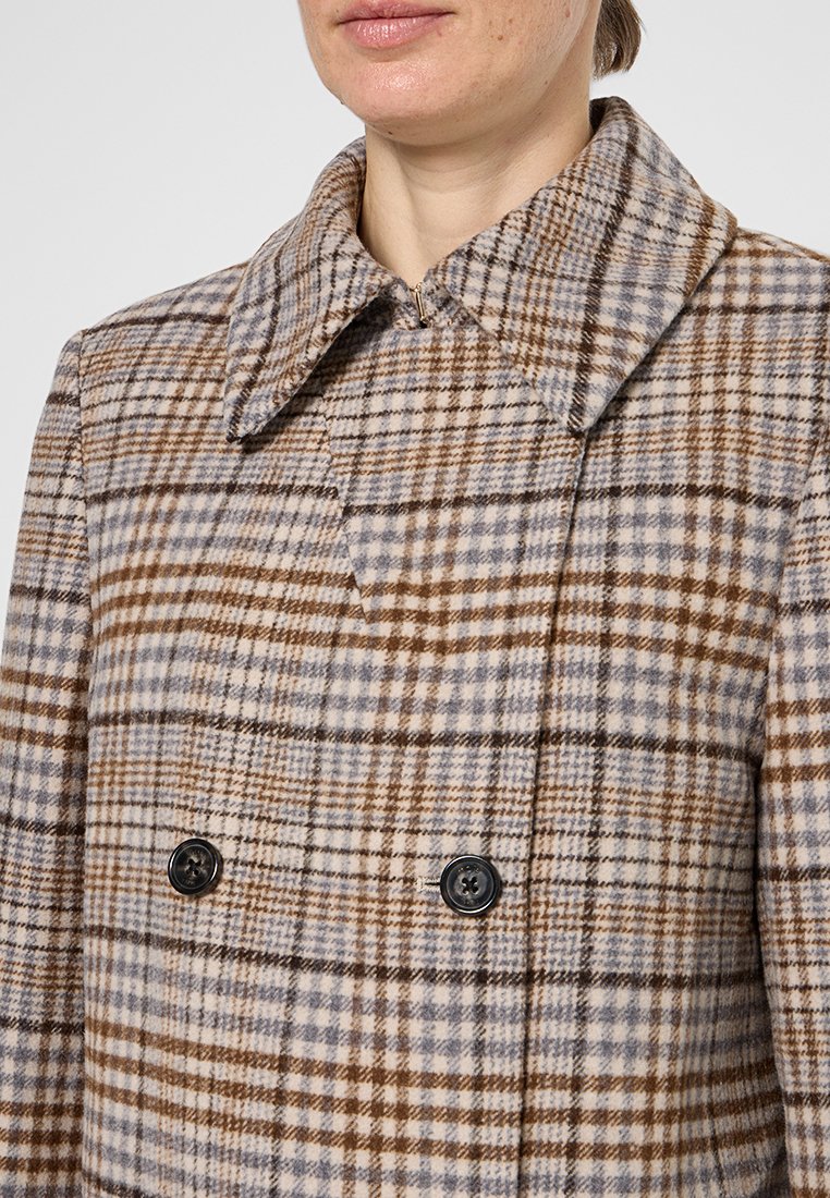 Dubbelzijdige jas in beige en bruine plaid, met een grote kraag en twee zwarte knopen aan de voorkant. Zachte stoftexture.