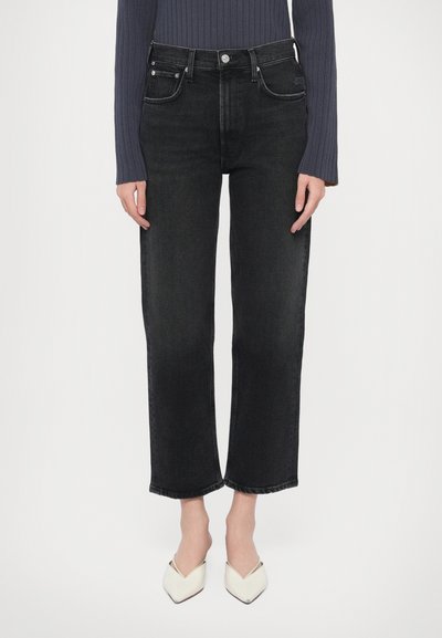 Black denim jeans with a straight-leg cut, featuring front pockets, a button closure, and subtle fading details. Paired with cream mules.