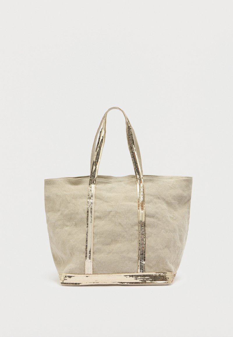 Sac fourre-tout en toile beige avec des anses et une base en métal doré, présentant un design simple et non structuré ainsi qu'une surface légèrement texturée.