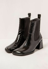 Botas negras de tobillo con un panel texturizado en cocodrilo brillante, lados elásticos y un tacón cuadrado y bloque. Acabado suave y dobles tiradores.