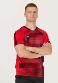 Punainen urheilupaita, jossa on vaakasuoria mustia raitoja, lyhyet hihat ja musta kaulus. Valkoinen FZ-logo rinnassa. Sujuva, kevyt materiaali.