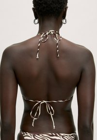 Gestreifter Bikini in Braun und Creme mit Halter-Trägern und einer Bindeschnalle im Rücken. Glatte Textur, minimales Hardware-Design und eine figurschmeichelnde Passform.