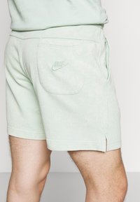 Helle grüne Nike-Shorts aus strukturiertem Stoff, mit einer Gesäßtasche und gesticktem Logo. Mit abgeschnittenen Säumen und seitlichen Schlitzen für zusätzlichen Komfort.