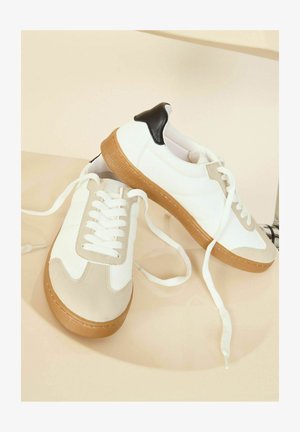 Hvide og beige sneakers med gummisål, snørebåndsdesign, læderdetaljer og sort hæltab. Glat tekstur med detaljeret syning.