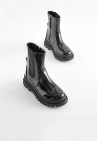 Schwarze Lackleder-Stiefeletten mit elastischen Seiteneinsätzen und einer dicken Gummisohle. Verfügt über einen Reißverschluss auf der Rückseite für einen einfachen Zugang.