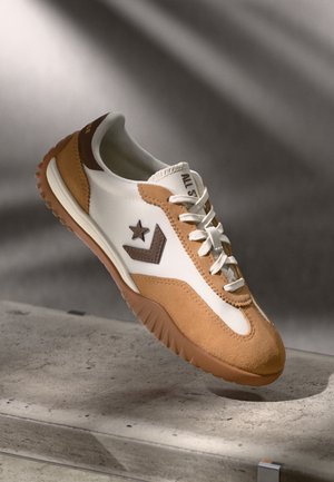 Pruunid ja kreemjad sneakerid, mis on valmistatud seemisnahast ja nahast, sisaldavad tähte logo, tekstureeritud kummist tallad ning valgeid paelu.