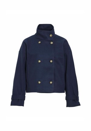Dyp blå, dobbeltspent jakke i strukturert stoff, med store knapper, høyt krage og oppbrettede ermer. Minimalistisk design, ingen synlige mønstre.