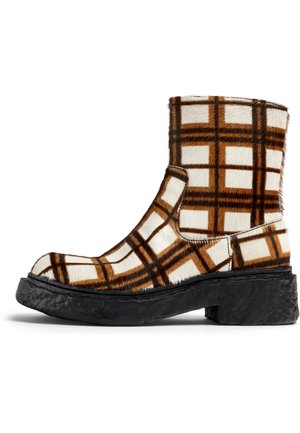 Bruin en witte geruite enkelboot gemaakt van faux fur met een dikke zwarte zool. Heeft een ronde neus en een elastische zijpaneel voor gemakkelijk aan- en uittrekken.