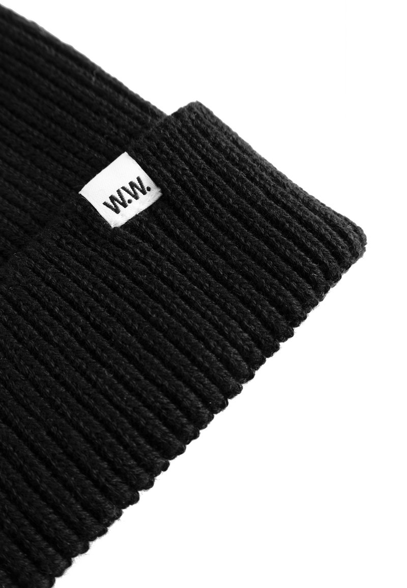 Black knit beanie with a ribbed texture, featuring a white tag marked "W.W." for branding. Simple design, no additional patterns or accents.