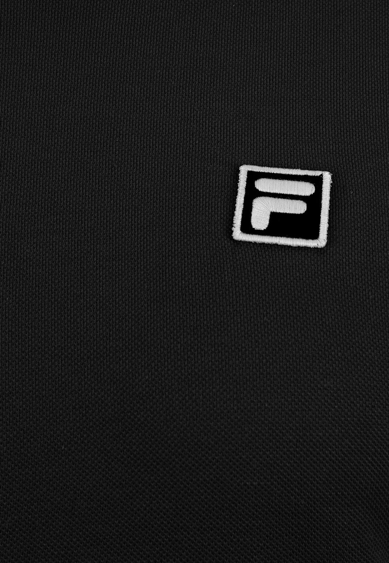 Tessuto nero con una leggera trama a righe presenta un logo Fila ricamato in bianco all'interno di un quadrato, posizionato nell'angolo in basso.