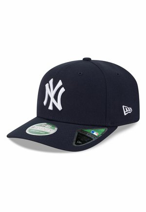 Dark navy blue New York Yankees cap with white embroidered logo and adjustment stickers on the curved brim.
