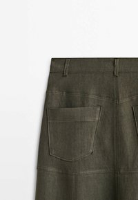 Dos d'une jupe en jean gris foncé avec passants de ceinture et deux grandes poches plaquées carrées, coutures visibles et détails de coutures.