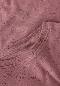 Sweter dziany w miękkim kolorze pudrowego różu z teksturowanym wzorem małych gwiazdek. Posiada okrągły dekolt i gładkie wykończenie wokół kołnierza.