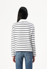 Long-sleeve polo shirt with navy stripes on a white background, featuring a classic collar and relaxed fit. Worn with blue jeans.