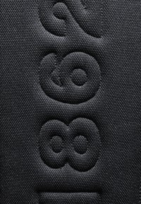 Svart texturerat tyg med präglade siffror och former, vilket skapar en taktil design med en matt finish och subtil lyster.