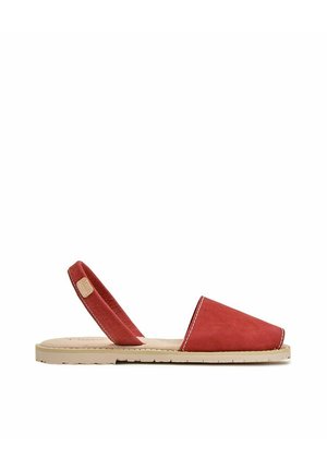 Sandalia plana roja con puntera abierta, suela beige y tira elástica trasera, vista lateral sobre fondo blanco.