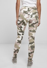 Leggins s kamuflažnim uzorkom u nijansama zelene, ružičaste i bijele boje, izrađeni od rastezljivog materijala, s visokim strukom i uskim krojem.