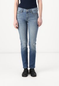 Light blue denim jeans with a slim fit, featuring slight distressing and fading, five pockets, and a classic button closure.