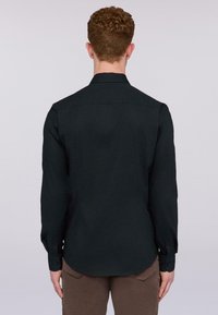 Camisa negra de manga larga hecha de tela suave con cuello, presenta puños abotonados y un dobladillo curvo, vista desde la parte posterior.