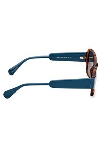 Ochelari de soare supradimensionați cu nuanțe de maro, cu brațe din acetat de culoare teal. Design unghiular, detalii din metal aurit și măsurători imprimate pe braț.