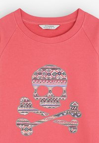 Sudadera de color coral con cuello de canalé y mangas raglán. Presenta un diseño de calavera y huesos cruzados impreso en patrones tribales multicolores.