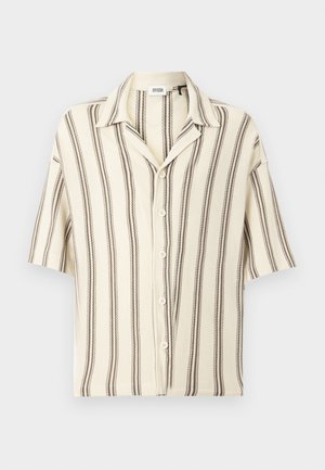 Kortærmet knappeskjorte i cremefarvet med brune lodrette striber. Har en klassisk krave og seks knapper foran. Tekstureret stof.