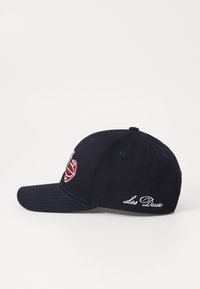 Sötétkék baseball sapka pamutból, hímzett kosárlabda grafikával és fehér "Les Deux" felirattal az oldalon. Ívelt karima.
