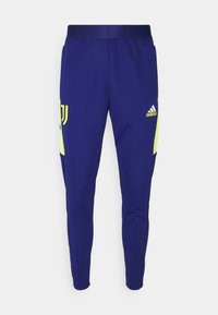 Granatowe spodnie sportowe o dopasowanym kroju, z żółtymi akcentami i logo, elastycznym pasem oraz teksturowanym materiałem.