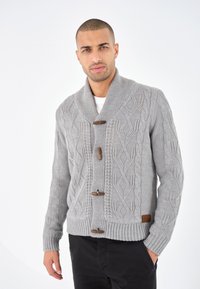 Grå stickad cardigan med sjalkrage, prydd med ett texturerat snörmönster, träknappar och ribbade ärmslut och nederkant.