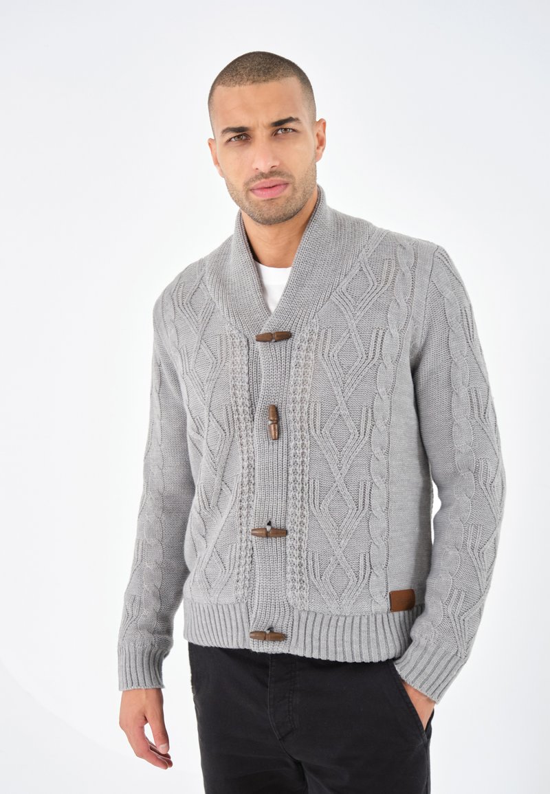 Grå stickad cardigan med sjalkrage, prydd med ett texturerat snörmönster, träknappar och ribbade ärmslut och nederkant.