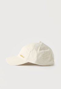 Μπεζ καπέλο μπεϊζμπολ από κορδόνι με καμπύλη γείσο και μικρό κίτρινο λογότυπο "Barbour" κεντημένο μπροστά αριστερά.