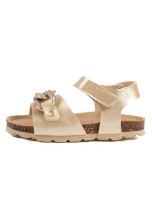 Sandale en cuir doré avec une finition texturée, présentant un détail de design noué et une sangle ajustable. Semelle ressemblant au liège pour une bonne adhérence et du confort.
