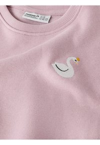 Jasnoróżowa bawełniana bluza z prążkowanym dekoltem, z haftowanym białym łabędziem z żółtą koroną po lewej stronie.