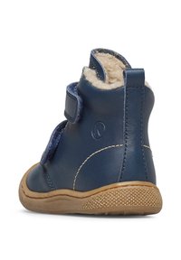 Stivale in pelle blu navy per bambino con fodera in pile beige, due fasce in velcro e una suola in gomma marrone texture, visto dal retro.