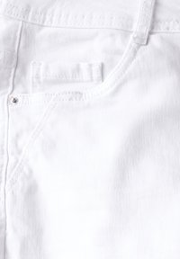 Vitt denimtyg med en subtil textur, med dekorativ sömnad, en liten ficka och en metallknapp som accent vid midjan.