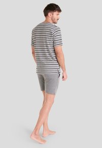 Camiseta de rayas grises con mangas cortas, combinada con pantalones cortos de color gris claro. Material de algodón, corte casual, con aberturas laterales visibles en la camiseta.