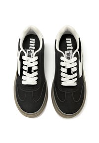 Baskets de sport noires avec des lacets blancs, présentant une tige texturée et une semelle en caoutchouc brun clair. Comprend un logo discret sur la languette.