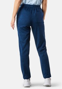 Marinblå träningbyxor med en texturerad, melerad finish. Har resårmidja och en avslappnad passform, lämpliga för aktiv träning.