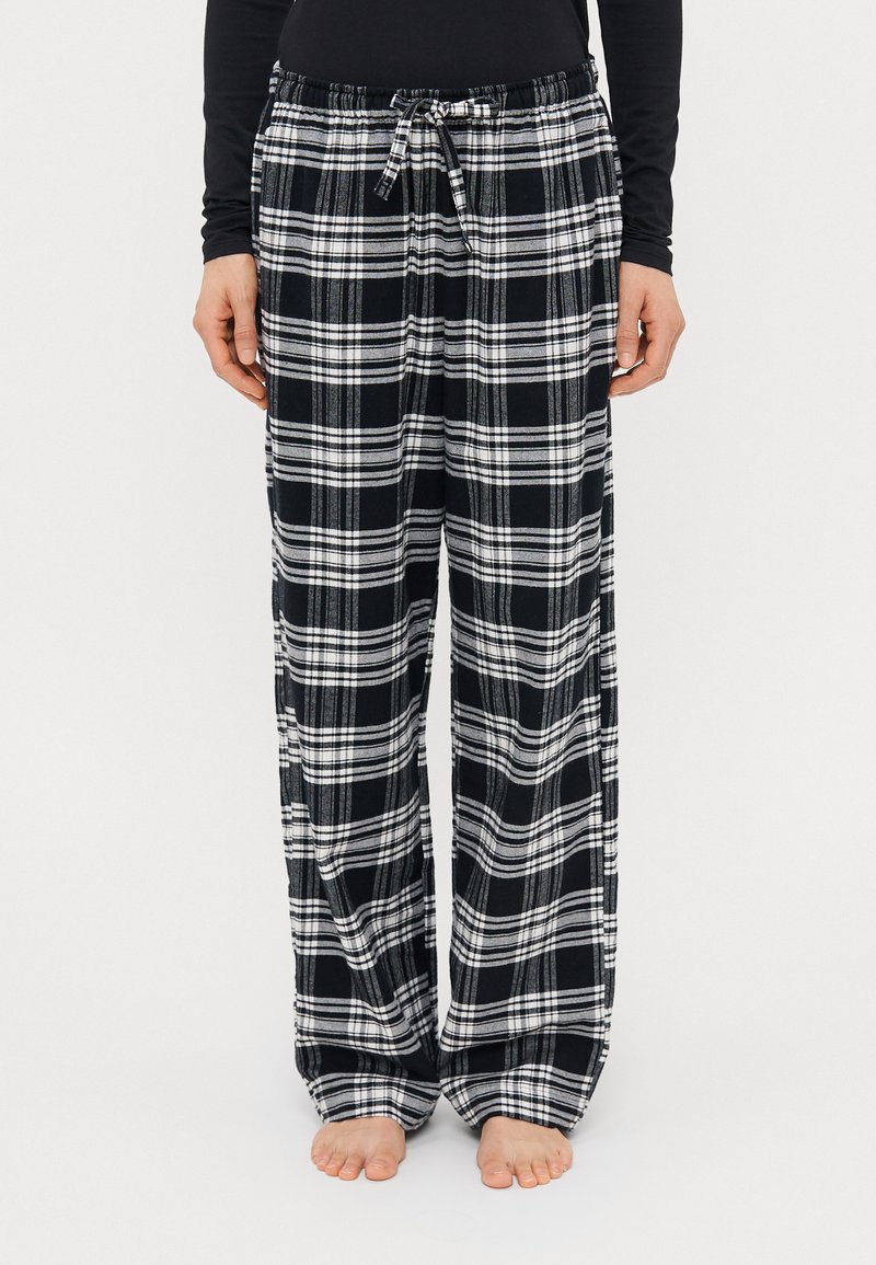 Sorte og hvide ternede pyjamabukser lavet af blødt stof, med en snor i taljen og løstsiddende design med brede ben.