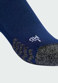 Calcetín azul marino con un talón y punta gris texturizados. Presenta un sutil patrón en zigzag en gris oscuro cerca del talón. Logo de la marca bordado en blanco.