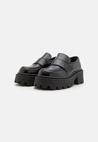 Zwarte platform schoenen met een glanzende afwerking, met een brede band over de bovenkant, dikke gestructureerde zool en een ronde neuspunt.